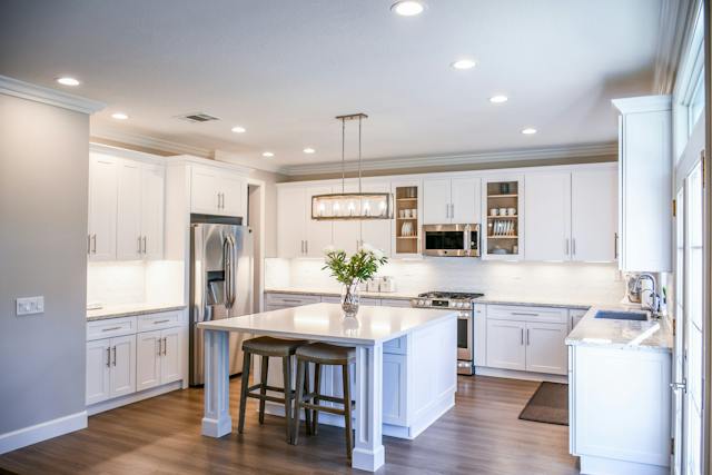 a white kitchen with hardwood flooring and stainless steel appliances